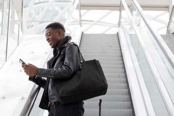 Wall Mural - young black man with cellphone and bag on escalator at station