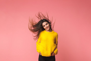 Sticker - Young emotional woman posing isolated over pink background shaking hair.