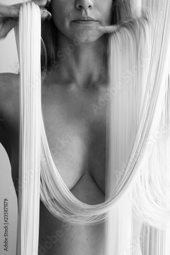 Zdjęcie XXL Atrakcyjne, seksowne, nagie ciało młodej, wspaniałej kobiety, częściowo zasłonięte przez białe nici spadającej kurtyny sznurkowej ozdobnej w piękne kształty.