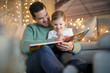 © goodluz - Father and daughter reading a story at home