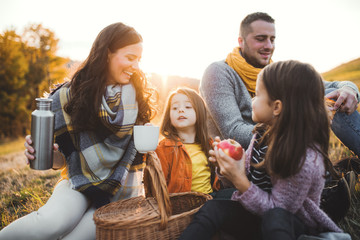 Wall Mural - A young family with two small children having picnic in autumn nature at sunset.