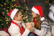 © Pixel-Shot - Loving young couple in Santa hats and with hot chocolate celebrating Christmas at home