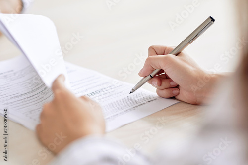 Fotomural Crop shot of person with pen signing contract at desk in daylight