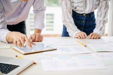 Wall Mural - crop shot of woman and man with tablet composing papers and creating new project in team