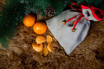 Tangerines with leaves in Christmas decor with Christmas tree.Christmas tree with wooden rustic decorations and presents under it in loft interior.Christmas composition with gift box and decorations.