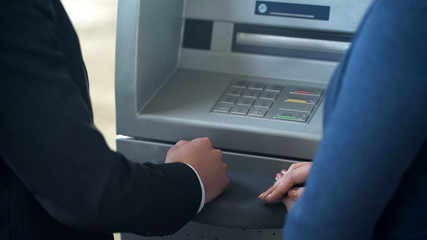 Wall Mural - Bank employee showing new client how to work with ATM, good service technologies