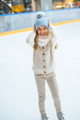 Wall Mural - smiling adorable kid in sweater and hat on skating rink