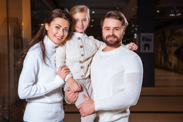 Wall Mural - portrait of smiling parents and daughter looking at camera