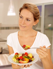 Canvas Print - WOMAN IN KITCHEN EATING FRUIT SALAD