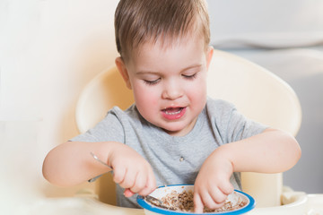 the kid eats buckwheat porridge in the kitchen