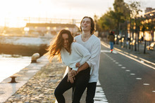Young Man Hugging Cheerful Woman On Footpath