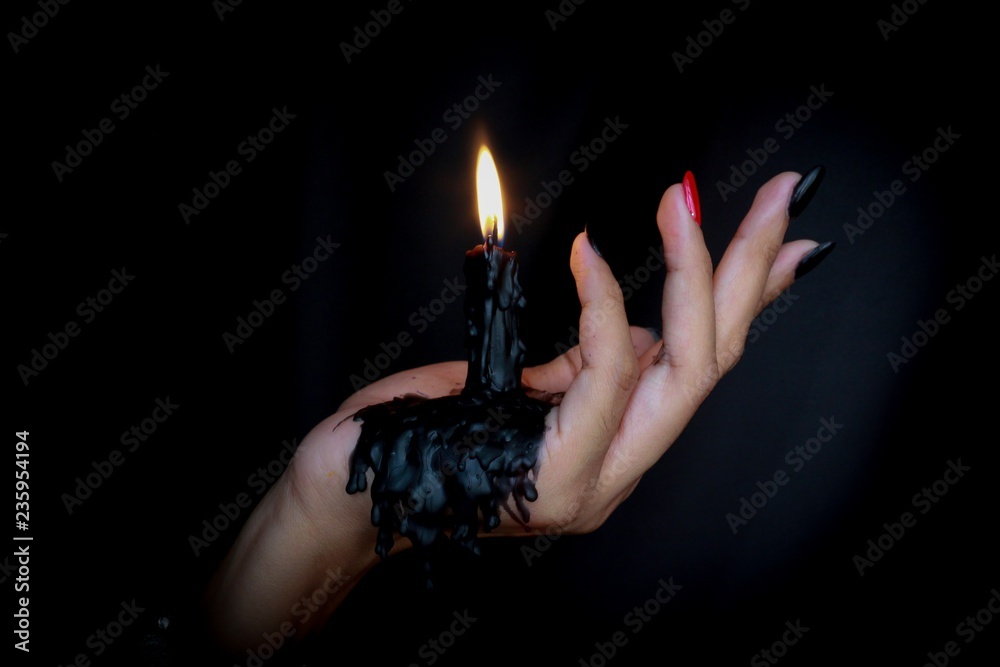 Black Candle melted on hand in black background. For halloween s concept. Felling darkness with light of flame burning from the supernatural. Stock Photo Adobe Stock