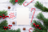 Fototapeta Nowy Jork - Christmas background. Fir branches, candy cane and gifts on a light wooden background. Cranberries, spices, holly berries. Flat lay, top view, copy space.