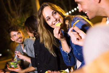 Attractive young group of friends visiting eat market and eating fast food in the street.