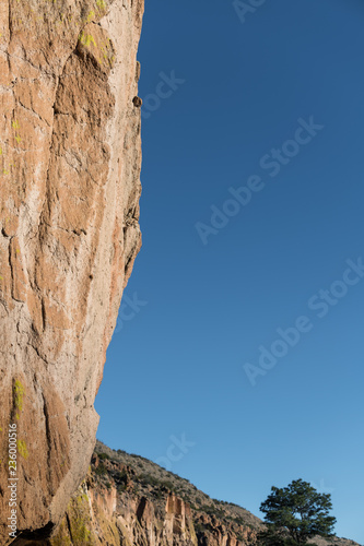 Fotografie, Obraz Vertical view of overhanging sandstone cliff with colorful lichen in Bandelier N