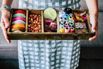 Above view of woman taking and showing fabrics buttons and accessories to make dress or jewels with a lot of colors and materiales - handcraft and handmade work job business concept