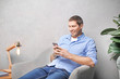 © Africa Studio - Young man in casual clothes using cell phone at home