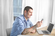 © Africa Studio - Young man in casual clothes using cell phone indoors