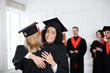 © Africa Studio - Happy students in bachelor robes hugging indoors, Graduation day