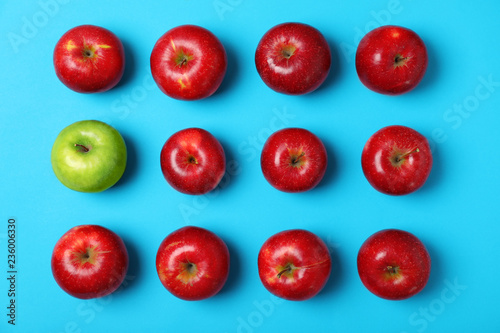 Fotomural Green apple among red ones on color background, top view