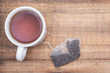 Cup and pyramid pouches of organic whole leaf earl grey tea on wooden background.