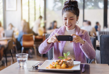 Wall Mural - woman using smartphone take photo of food before eating in restaurant