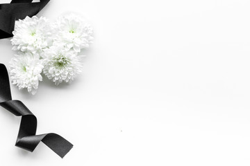 Wall Mural - Funeral symbols. White flower near black ribbon on white background top view space for text