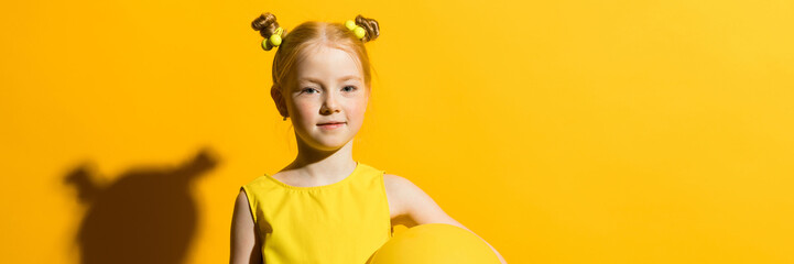 Wall Mural - Girl with red hair on a yellow background. The girl is holding a yellow air balloon.