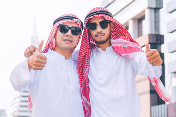 Two Arab businessmen standing by raising both hands up in city