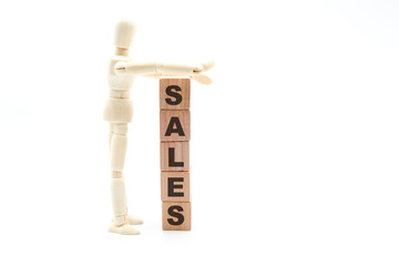 Wall Mural - Wooden figure as businessman building Sales as tower of wood cubes