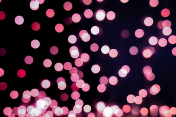 Red and pink Christmas tree bokeh on black background of defocused glittering lights, Christmas background pattern concept