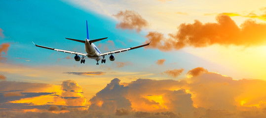 Airplane flying above dramatic clouds during sunset