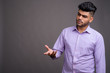 © Ranta Images - Young handsome Indian businessman against gray background