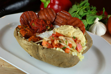 Wall Mural - Kumpir - Traditional Turkish meal with baked potato, butter, cheese, bulgur salad, beef sausage and hot spices