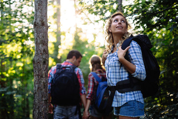 Wall Mural - group of young and happy people hiking in forest