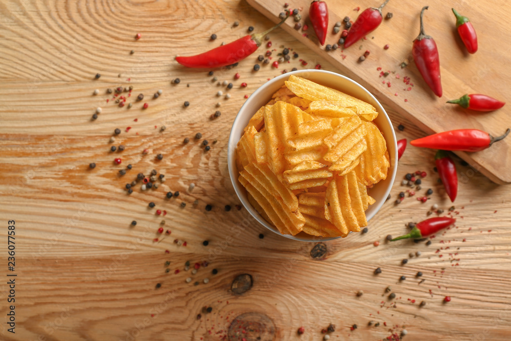 Bowl with tasty potato chips on wooden background