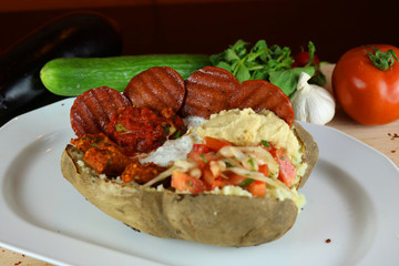 Wall Mural - Kumpir - Traditional Turkish meal with baked potato, butter, cheese, bulgur salad, beef sausage and hot spices