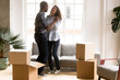 © fizkes - Happy African American couple in love dancing after moving in new house, attractive smiling woman and man celebrating relocating, cardboard boxes with belongings, homeowners in new apartment