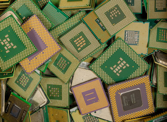 An assorted pile of CPUs removed from computers for recycling. The pins on most of them are gold plated.