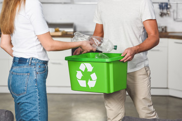 Wall Mural - cropped view of woman putting empty plastic bottles in recycle green box