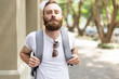 © Mangostar - Relaxed bearded guy enjoying vacation. Tired young man wearing summer clothes, carrying heavy backpack and looking at camera. Vacation in warm countries concept