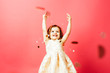 © Carlos David - Portrait of an excited small toddler child throwing confetti and looking up, isolated on pink studio background