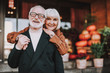 © Yakobchuk Olena - Waist up portrait of happy lady hugging husband from behind while he holding her hand. They looking at camera and smiling