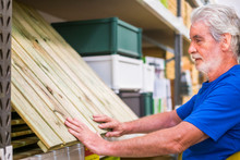 Caucasian Man Choose Articles In Hardware Store - Wood Floor Like Pallets To Build Furnitures Or Ground At Home - Business Concept For Retired People Like To Do Activities