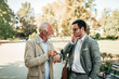 © bnenin - Young elegant man is late to a meeting with a senior man outdoors.