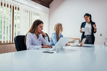 Wall Mural - Three young business women at the meeting in a conference room.