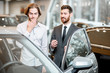 Car salesman helping a young ashamed client to make a decision showing intrerior of a luxury car at the showroom