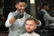 © serhiibobyk - Barber doing trendy haircut to young man in barber shop