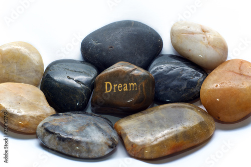 Fotografia, Obraz A brown polished river stone with the word dream on it surrounded by many other rocks