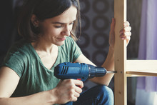 Beautiful Young Woman Holding Screwdriver And Repairing Or Making Wooden Shelf
